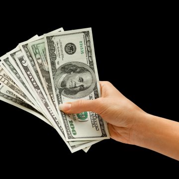 hand holding dollar bills black background payday loans